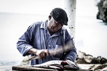 man cutting raw fish using knife