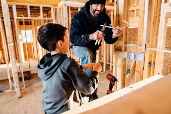 Man Cutting White Cable Beside Boy In Grey Hoodie