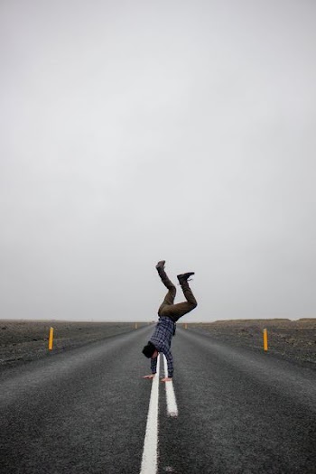 man doing handstand on middle of concrete pavement