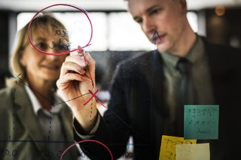Man Drawing on Clear Board Using Red Marker