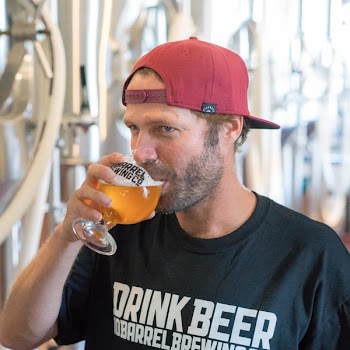 Man Drinking Liquor Wearing Red Cap and Black Crew-neck Shirt