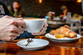 Man drinks cappuccino and eats croissant