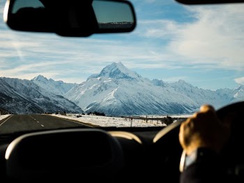 man driving towards mountain coated with snow