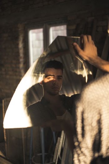 man facing direction of camera from broken mirror