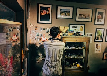 Man Facing Photos Attached on Wall