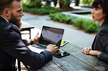 man facing woman with laptop on table