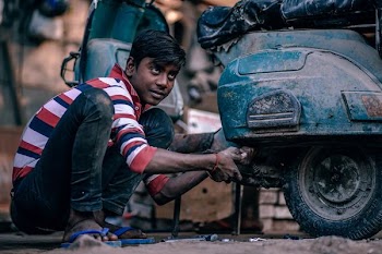 man fixing black motorcycle