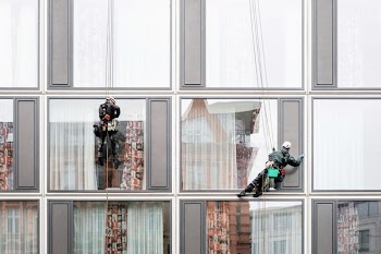 man hanging beside building window
