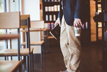 man holding a book and plastic cup