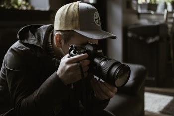 Man Holding and Taking Photo Using Black Dslr Camera