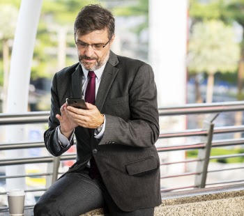 Man Holding Android Smartphone Sitting on Brown Marble Pavement