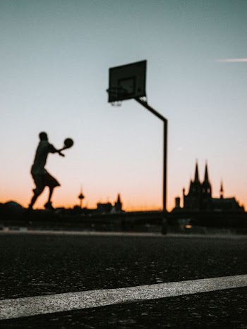 man holding ball jumping near portable basketball hoop