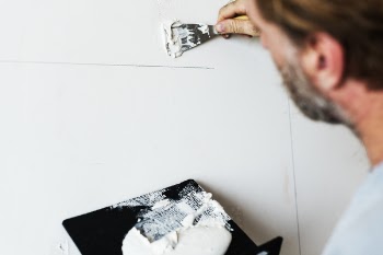 Man Holding Black Board With White Paint, Painting Wall