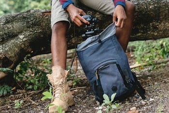 man holding black camera and gray camping backpack