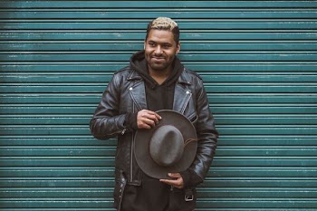 man holding black cowboy hat standing in front of roll-up door