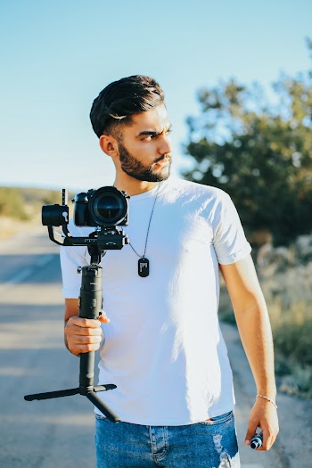 Man Holding Black Dslr Camera With Stabilizer