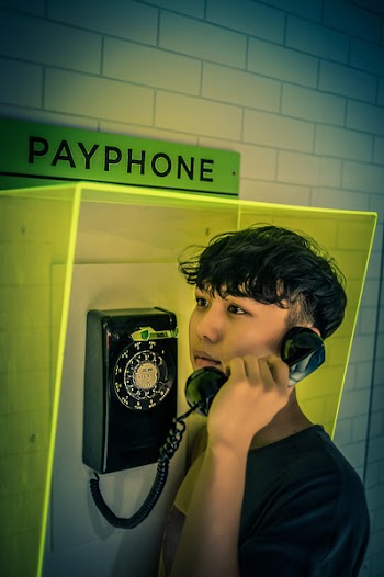 Man Holding Black Rotary Payphone
