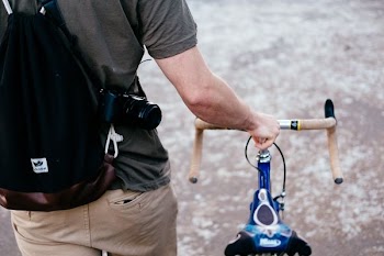 man holding brown and blue bicycle while walking outdoor during daytime