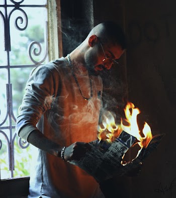 Man Holding Burning Paper by the Window