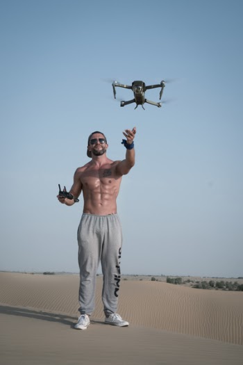 Man Holding Drone Remote Standing on Gray Concrete Pavement