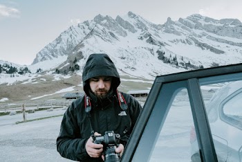 Man Holding Dslr Camera Beside Vehicle
