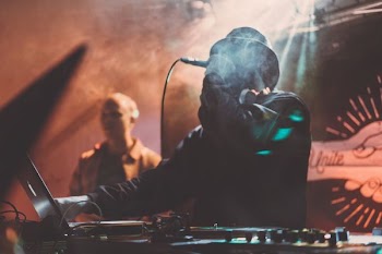 man holding dynamics microphone in front of DJ turn table