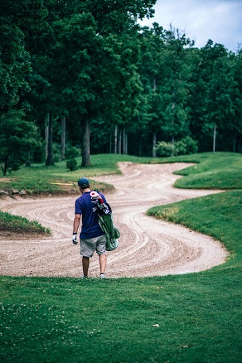 Man Holding Golf Bag Walks on Golf Field