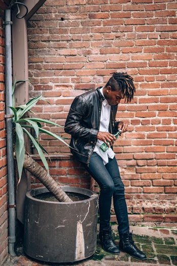 man holding green bottle near brown concrete wall