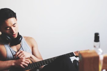man holding guitar wearing headphones