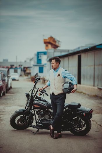 man holding helmet standing beside motorcycle