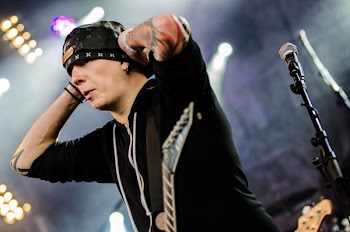 Man Holding His Black Cap Near Black Microphone on Stand