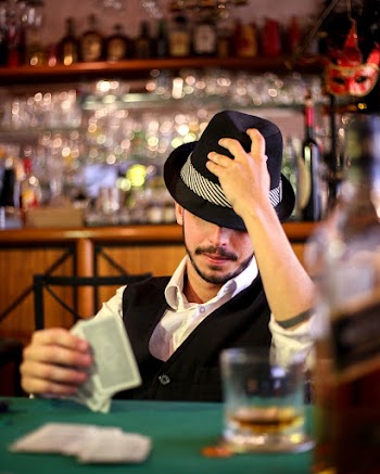 Man Holding His Hat While Playing Cards