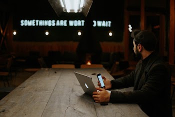 Man Holding Laptop and Smartphone
