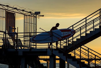 man holding paddle board during golden hour