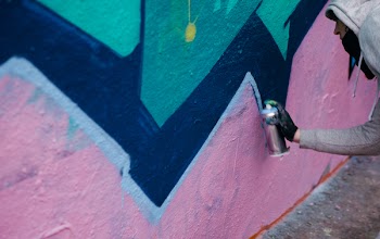 Man Holding Paint Spray Can in Front of Wall