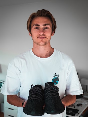 Man Holding Pair Of Black Adidas Yeezy Boost 350 Shoes