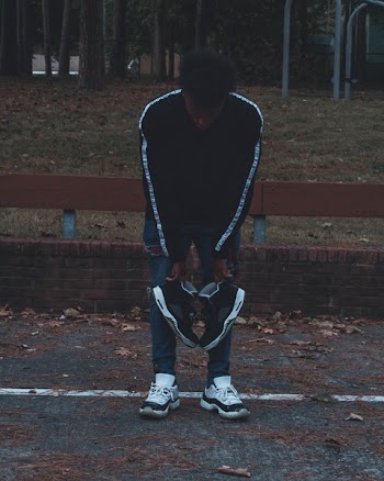 Man Holding Pair of Black Athletic Shoes