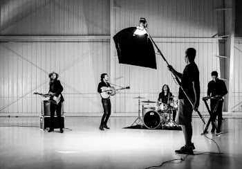 man holding pole with light while band having jam session