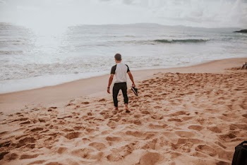 Man Holding Shoes on Shore