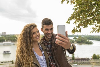 Man Holding Smartphone Beside Woman Near Tree