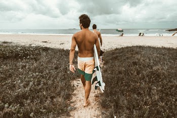 Man Holding Surfboard While Walking To the Beach