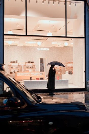 man holding umbrella standing beside store during daytime