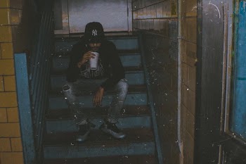 Man Holding White Cup Sitting on Stairs