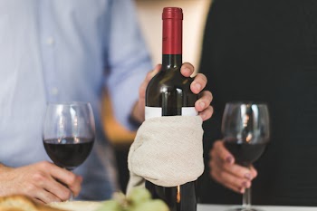 Man Holding White Labeled Red Wine Bottle Near Wine Glasses