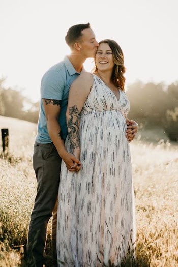 man holding woman's hand while kissing in forehead during daytime