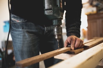 Man Holding Wooden Stick While Drilling Hole