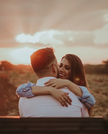 Man Hugging Woman While Sitting on Bench