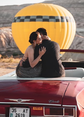 Man Hugging Woman While Sitting on Car
