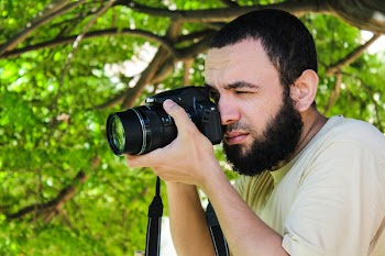 Man in Beige Shirt Taking Photo Using Black Dslr Camera Beside Tree