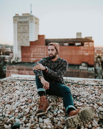 man in black and brown dress shirt seating on rocks